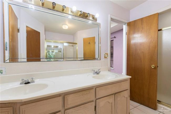 Full bath with double vanity, a shower stall, and tile patterned flooring | Image 14