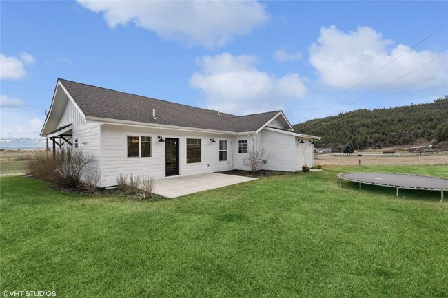 Rear view of house with a trampoline, a patio, roof with shingles, and a lawn | Image 37