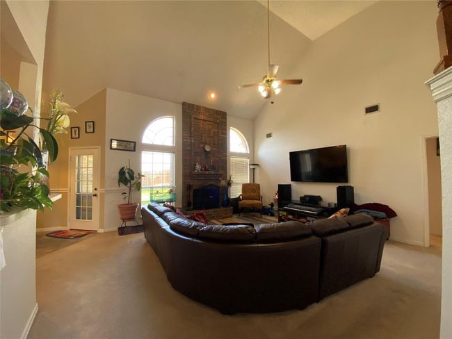 Living room with a large fireplace, carpet floors, high vaulted ceiling, and ceiling fan | Image 13