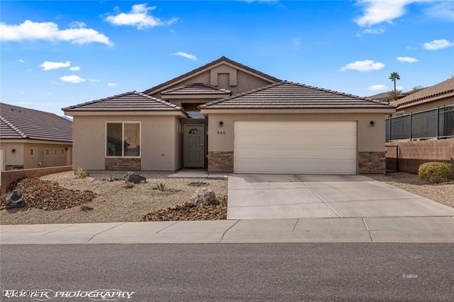 Ranch-style home featuring stucco siding, stone siding, fence, a garage, and concrete driveway | Image 6