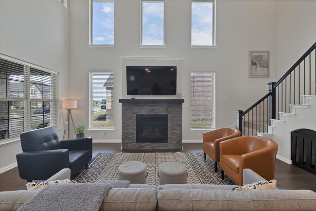 Living room with dark wood finished floors, baseboards, a fireplace, and a towering ceiling | Image 5