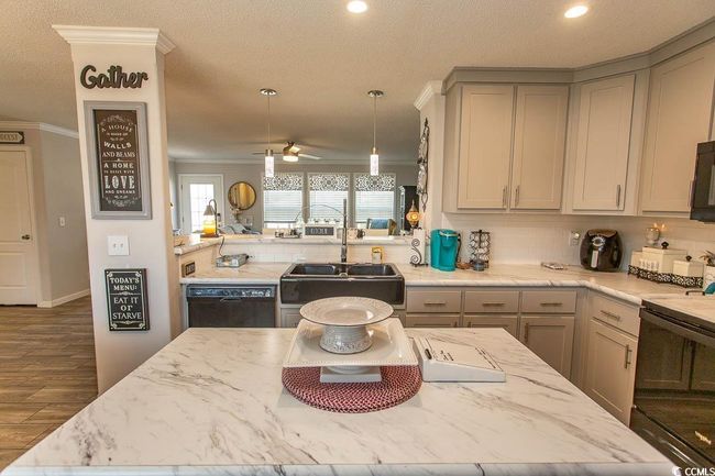 Kitchen featuring a sink, gray cabinets, tasteful backsplash, crown molding, and black appliances | Image 8