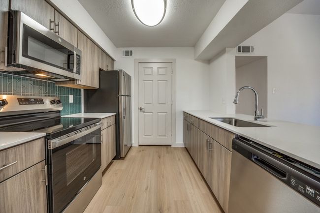 Kitchen with light hardwood / wood-style floors, a textured ceiling, sink, backsplash, and stainless steel appliances | Image 9