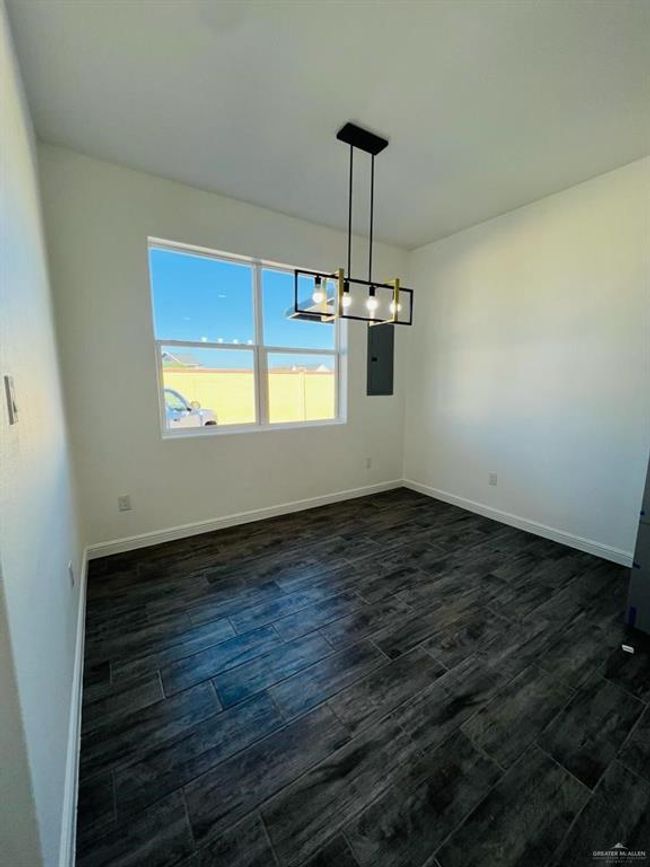 Unfurnished dining area featuring electric panel and dark hardwood / wood-style flooring | Image 8