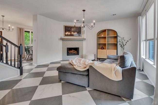 Living room with a chandelier, a tiled fireplace, and stairs | Image 9