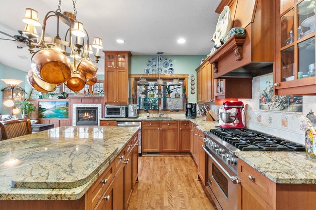 Kitchen showing breakfast bar / food prep area, Viking natural gas stove, cherry cabinets and pass through to screen porch. Sink includes instant hot water and garbage disposal. | Image 7