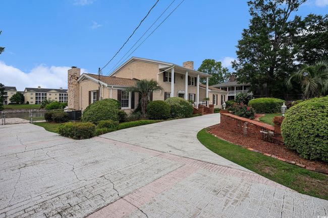 View of front of home with a chimney, curved driveway, and central air condition unit | Image 4