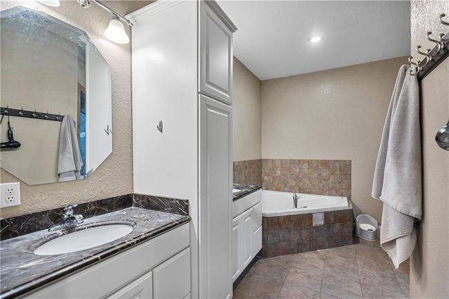 Bathroom with a relaxing tiled tub and vanity | Image 28