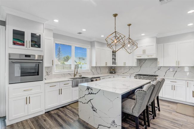 Kitchen featuring appliances with stainless steel finishes, a sink, crown molding, a center island, and white cabinets | Image 8