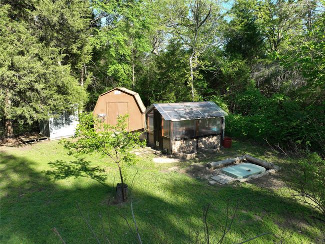 View of yard featuring an outbuilding, a storage unit, greenhouse, and ground storm shelter | Image 12