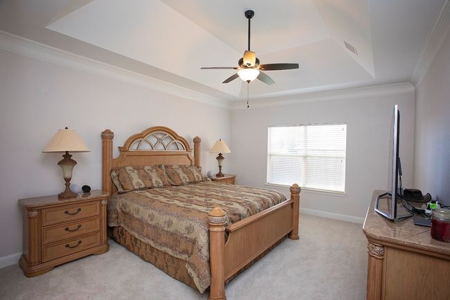 Bedroom featuring crown molding, arched walkways, light colored carpet, ceiling fan, and ensuite bath | Image 9