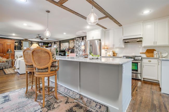 Kitchen featuring a kitchen island, dark wood-style floors, stainless steel appliances, and range hood | Image 10