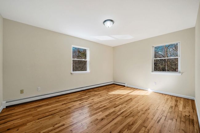 Spare room with a baseboard radiator, a skylight, hardwood / wood-style flooring, and baseboards | Image 16