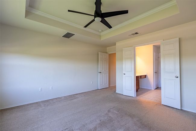 Unfurnished bedroom featuring a tray ceiling, crown molding, light carpet, and ceiling fan | Image 13
