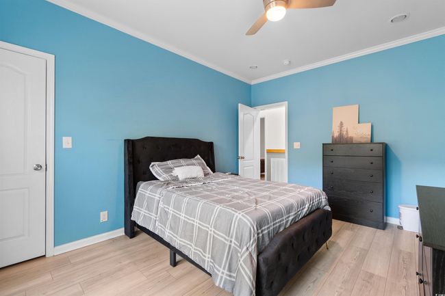 Bedroom featuring wood finished floors, baseboards, crown molding, and a ceiling fan | Image 18