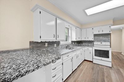 Kitchen featuring light hardwood / wood-style flooring, crown molding, white electric stove, and white cabinets | Image 3