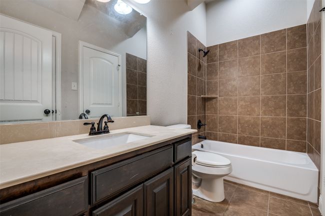 Full bathroom featuring vanity, shower / bath combination, a textured wall, and tile patterned flooring | Image 22