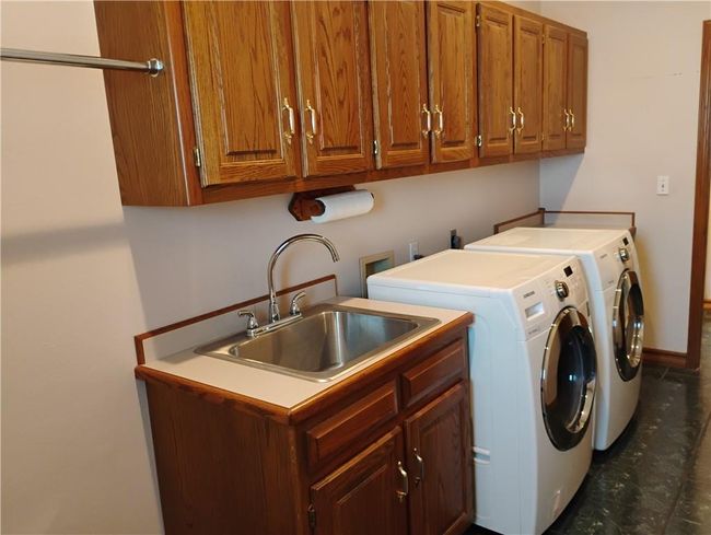 Washroom with cabinet space, a sink, and independent washer and dryer | Image 38