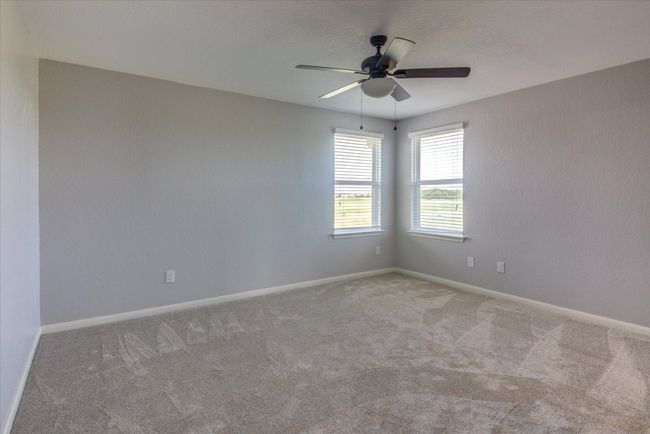 Large, open primary bedroom featuring a ceiling fan and fresh carpet. | Image 22