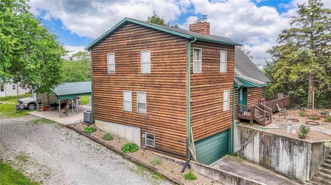 View of property exterior with a chimney, a garage, driveway, and a shingled roof | Image 57