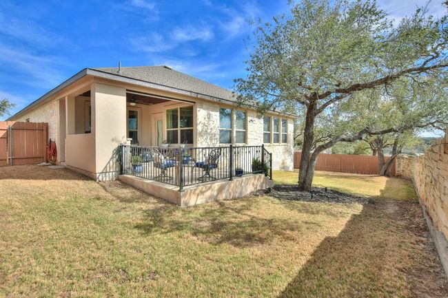 Rear view of house featuring a yard, stone siding, a fenced backyard, and a patio area | Image 33