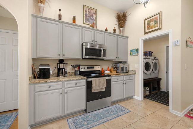 Kitchen featuring appliances with stainless steel finishes, separate washer and dryer, arched walkways, and light tile patterned flooring | Image 6