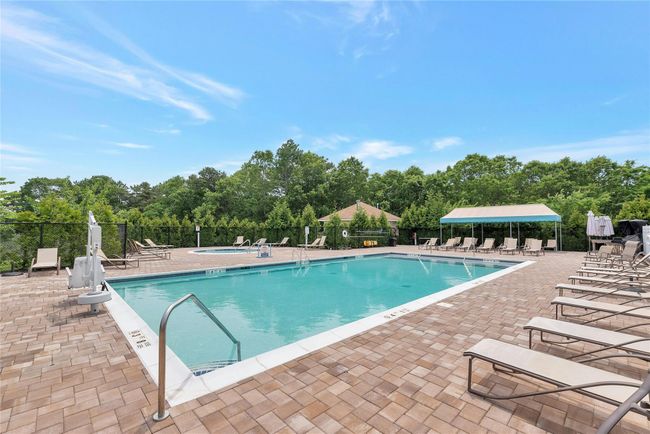 Community pool with a patio area and view of scattered trees | Image 18