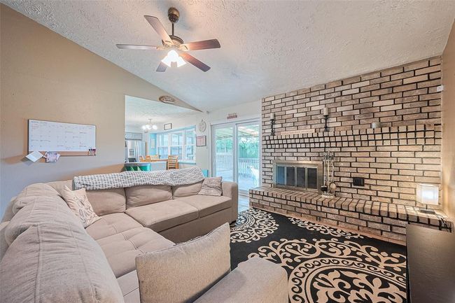 The living room showcases elegance and warmth, featuring a gas fireplace, soaring vaulted ceilings, and an abundance of natural light. | Image 6