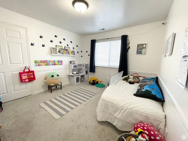 Spacious guest bedroom featuring a textured ceiling and carpet flooring | Image 15