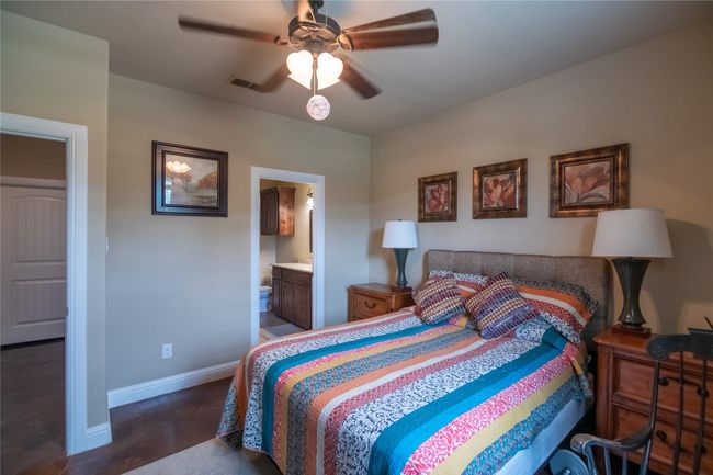 Bedroom with baseboards, finished concrete flooring, ceiling fan, and ensuite bath | Image 23