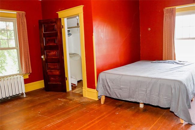 The north Bedroom featuring baseboards, multiple windows, radiator heating unit, and original hardwood floors | Image 32