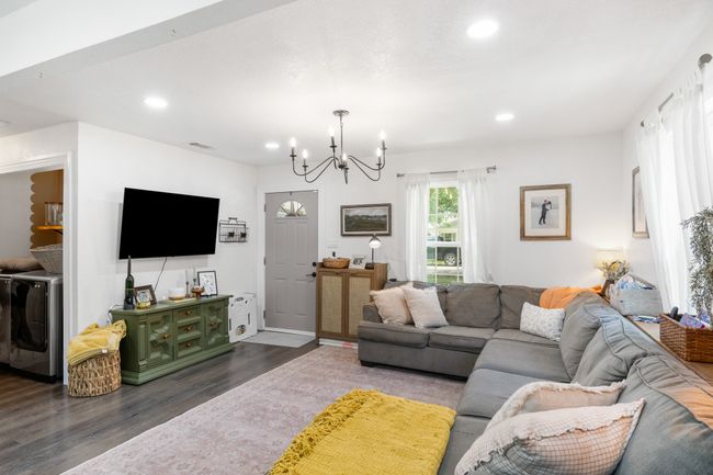 Living room with a chandelier, dark wood-type flooring, washer / dryer, and recessed lighting | Image 13
