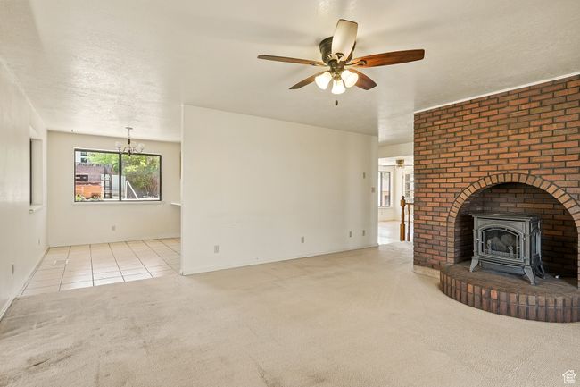 Unfurnished living room featuring a wood stove, carpet floors, ceiling fan, a chandelier, and a textured ceiling | Image 9