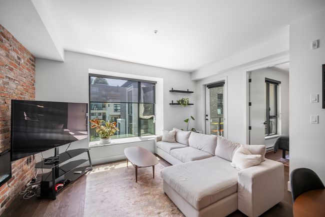 Living area with brick wall and wood finished floors | Image 6