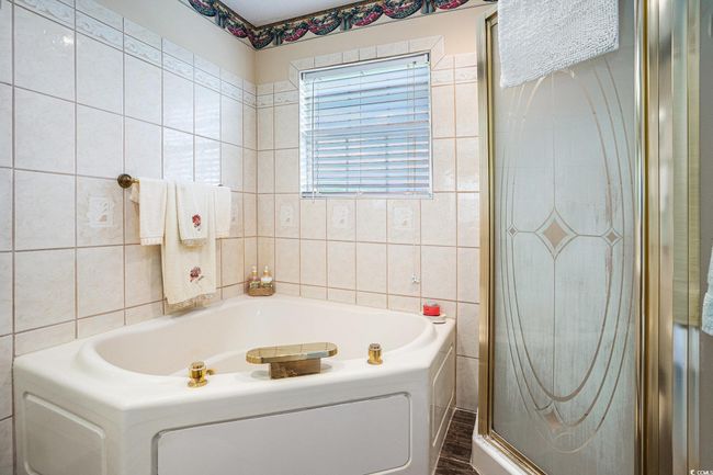 Bathroom featuring tile walls, a garden tub, and a shower stall | Image 26