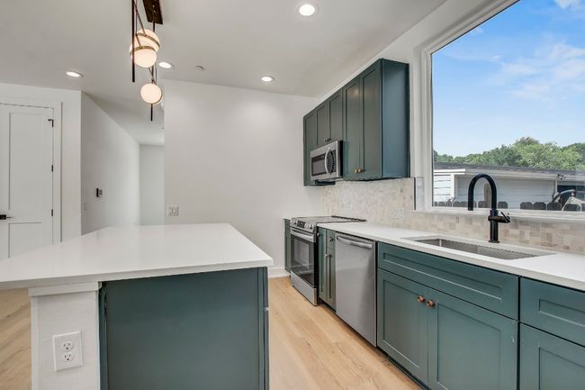Kitchen featuring stainless steel appliances, a sink, decorative backsplash, recessed lighting, and a kitchen island | Image 4