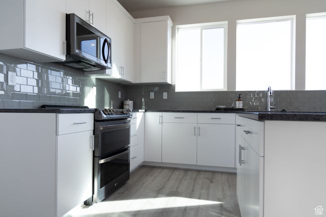 Kitchen featuring double oven range, dark countertops, a sink, and decorative backsplash | Image 12