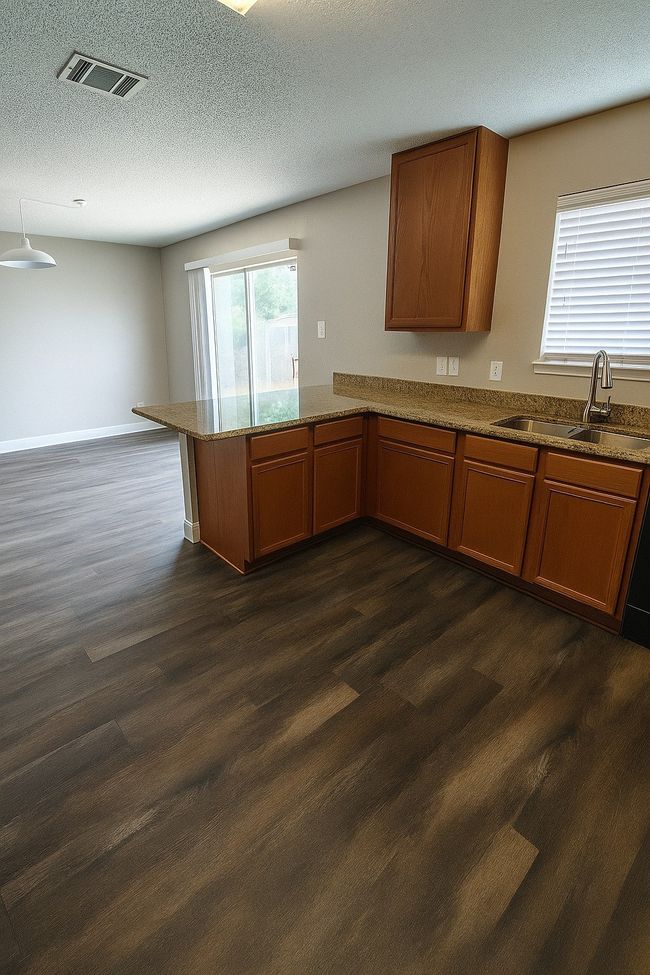 Kitchen with a peninsula, brown cabinetry, dark wood finished floors, and a textured ceiling | Image 22