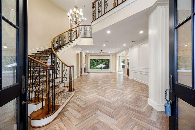 Once inside the double-doored entry, you are welcomed with a winding wooden stairway with a carpeted path to the upstairs secondary bedrooms. | Image 5