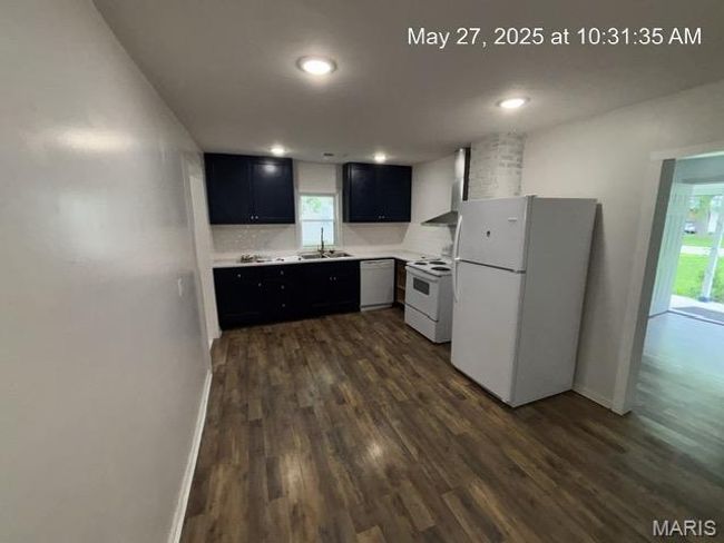 Kitchen with white appliances, dark cabinets, dark wood-type flooring, light countertops, and baseboards | Image 4