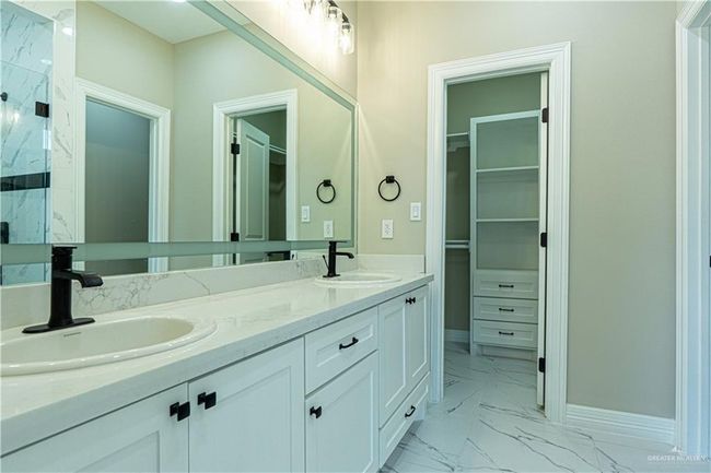 Bathroom with marble finish floor, a marble finish shower, a walk in closet, and a sink | Image 31