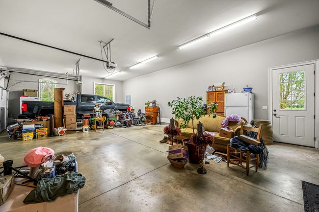 A 3 car garage with stained floors and a safe room offers both practicality and enhanced security for homeowners. Stained concrete floors add a polished appearance to the garage, and also offer durability and ease of maintenance. | Image 64