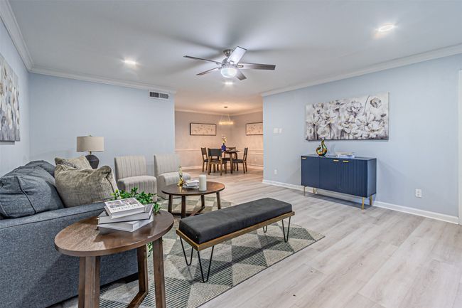 Living room with a ceiling fan, baseboards, light wood-type flooring, visible vents, and ornamental molding | Image 6