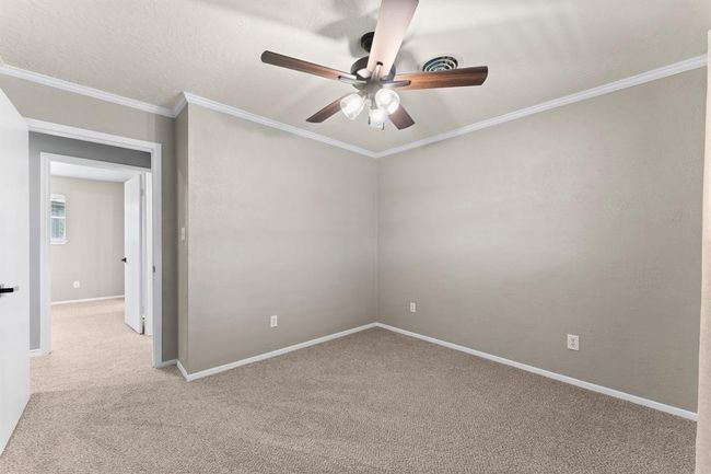 This bedroom features neutral walls, carpeted flooring, and a ceiling fan with lights. | Image 23
