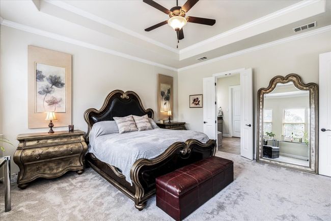 Carpeted bedroom with a tray ceiling, ornamental molding, and ceiling fan | Image 18