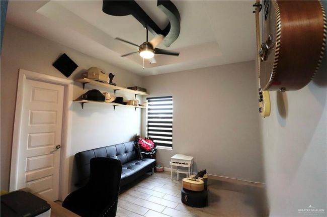 Music room/home office with a ceiling fan, a raised ceiling, and baseboards | Image 15