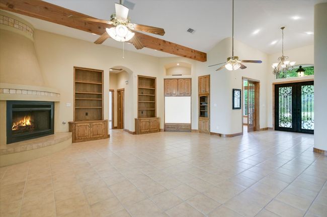 The full beauty of this room is best when viewed in person! The dynamic of melding the old world fireplace, warm wood built-ins for collections and media along with vaulted/beamed ceilings with recessed, fans and natural lighting with a neutral tile leaves room for your own unique blend of design and color palette to be seen as you enter the foyer through the ornate iron doors. | Image 7
