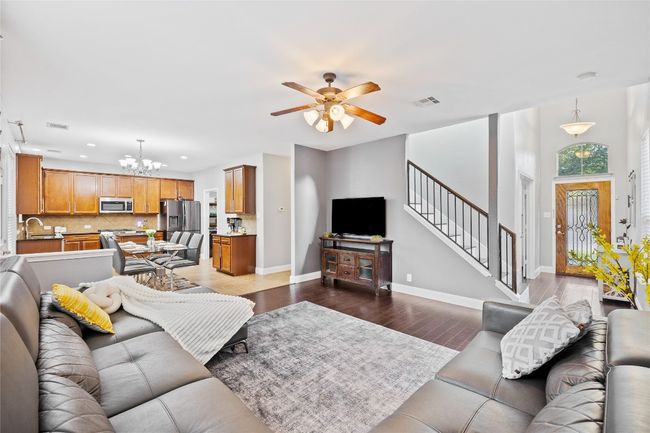 Living area featuring a chandelier, stairs, dark wood-style flooring, recessed lighting, and ceiling fan | Image 5