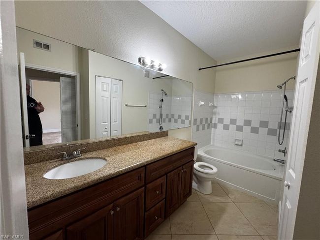 Bathroom featuring tile patterned floors, toilet, shower / bathtub combination, vanity, and a textured ceiling | Image 7
