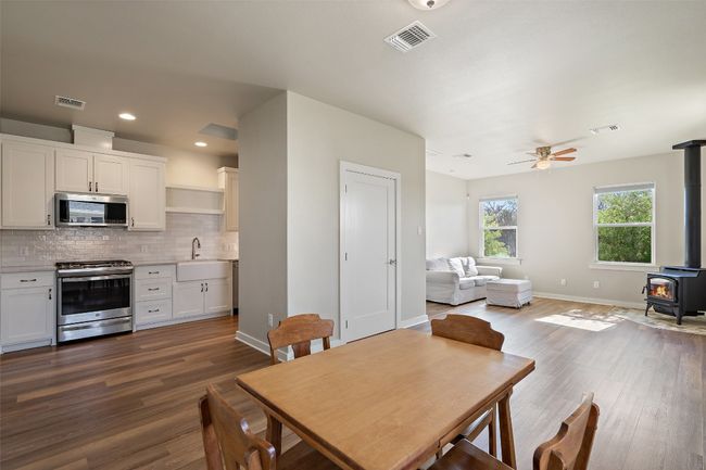 Dining room with a wood stove, a ceiling fan, dark wood-type flooring, baseboards, and recessed lighting | Image 31